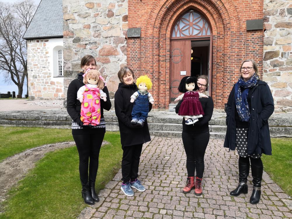 Halikon kirkon edessä kirkkonuket Klaara, Pekka ja Auli nukettajiensa kanssa sekä Annukka-pappi.