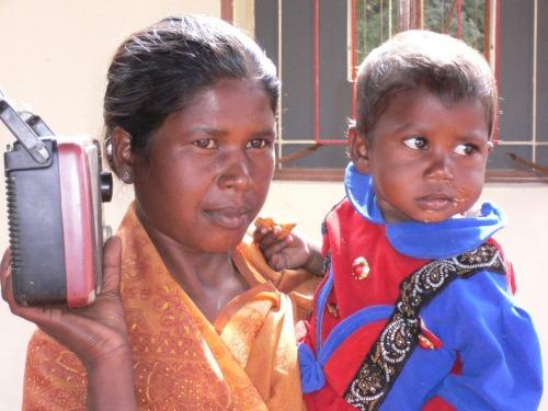 Intialainen nainen, jonka toisessa kädessä on radio ja toisessa pikkulapsi