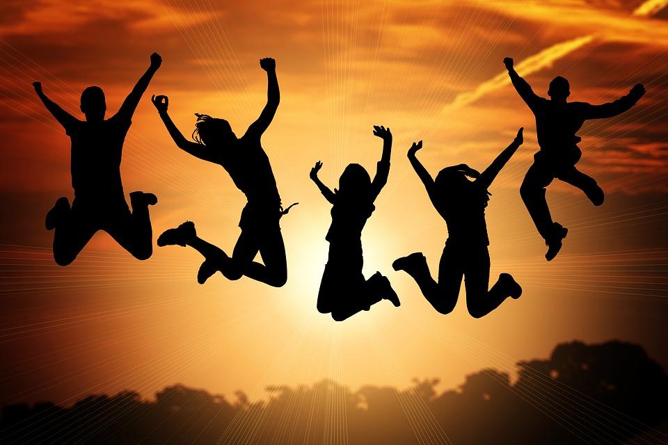 Viisi nuorta hyppää ilmaan, auringonlasku taustalla