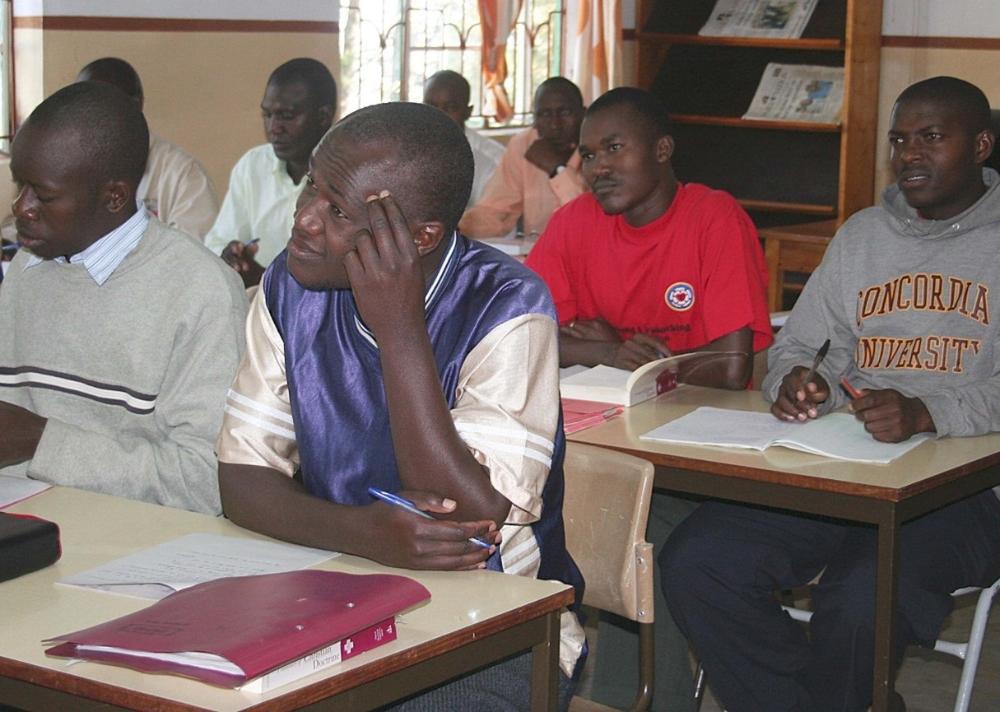 Kahdeksan afrikkalaista nuortamiestä istuu pulpetin ääressä ja opiskelee.