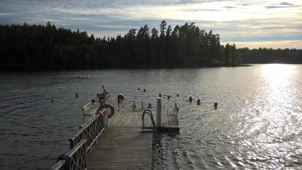 Laituri ja laiturin edessä ihmisiä uimassa järvessä