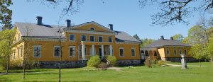 Keltainen komea 1800-luvun kartanon päärakennus keväisessä maisemassa