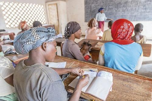Afrikkalaiset naiset istuvat lukutaitoluokassa.